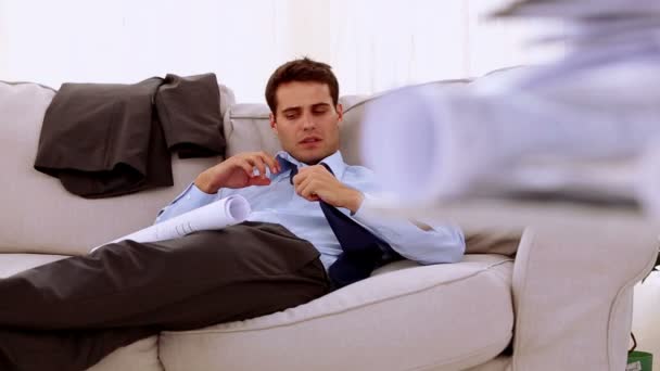 Бизнесмен лежит на диване и смотрит на документ — стоковое видео
