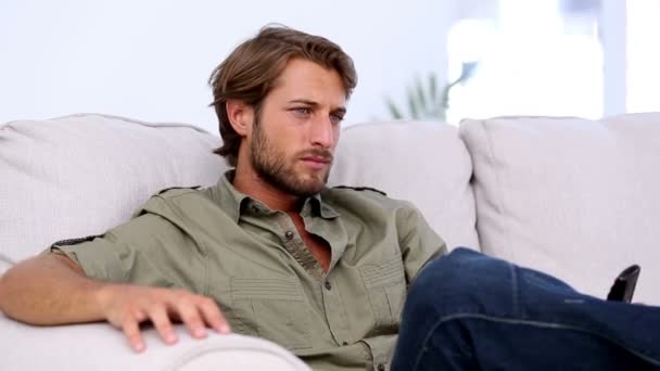 Attractive man watching TV and holding remote — Stock Video