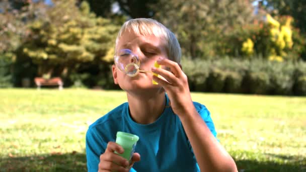 Jovem rapaz soprando em uma varinha de bolha — Vídeo de Stock