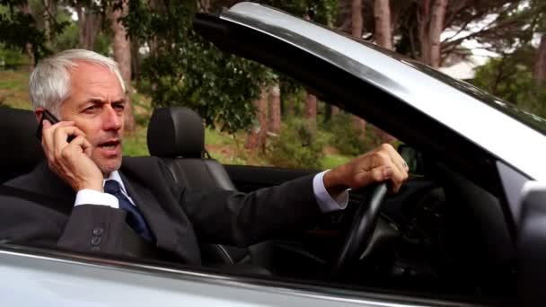 Businessmanon de telefoon in zijn converteerbare auto — Stockvideo