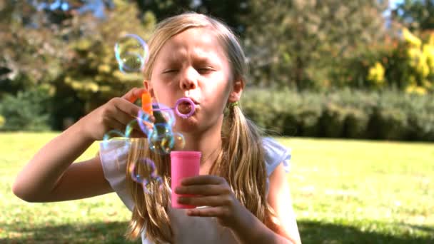 Jeune fille soufflant dans une baguette à bulles — Video