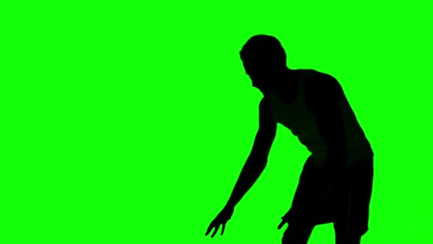 Silhouette eines Mannes, der einen Basketball auf eine grüne Leinwand wirft — Stockvideo