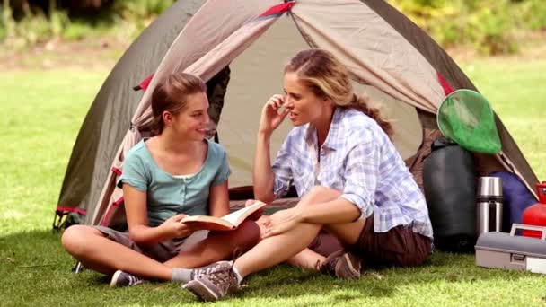 Mãe e filha lendo um livro na frente de sua tenda — Vídeo de Stock