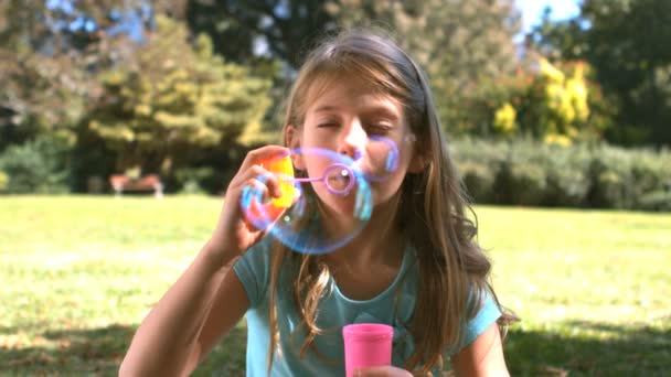 Linda chica joven soplando en una varita de burbuja — Vídeo de stock