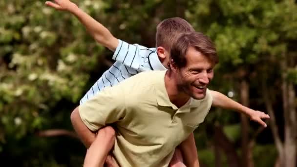 Vader aan zijn zoon geven een piggy back — Stockvideo