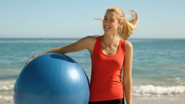 Gelukkige vrouw met gymnastiek bal op het strand — Stockvideo