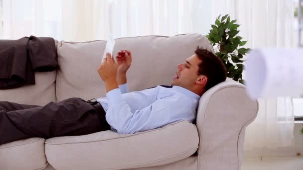 Tired businessman using his tablet on a couch — Stock Video