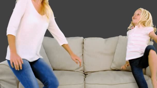 Mother and daughter jumping on the sofa on grey background — Stock Video