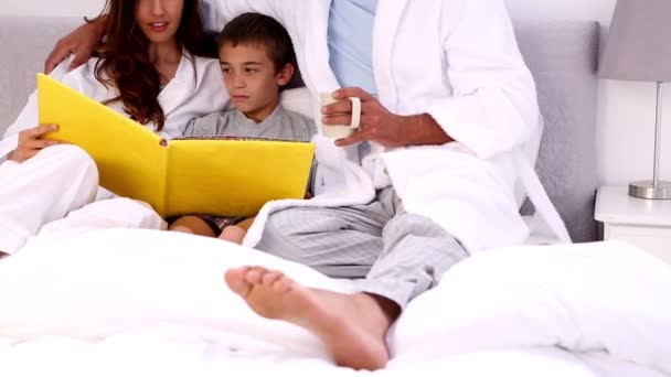 Padres y su hijo leyendo libro — Vídeo de stock
