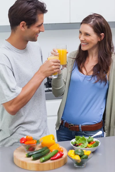 Schönes Paar klirrt mit einem Glas Orangensaft — Stockfoto