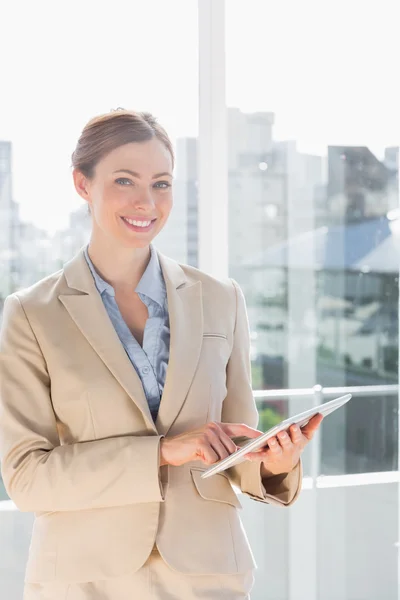 Beautiful businesswoman using her tablet pc and smiling at camer — Stock Photo, Image