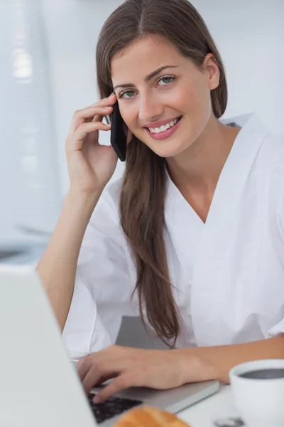 Allegro telefono donna e utilizzando il suo computer portatile — Foto Stock