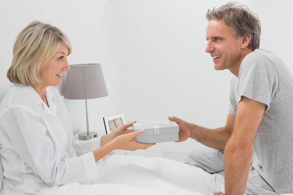 Homem dando presente ao seu parceiro sorridente — Fotografia de Stock