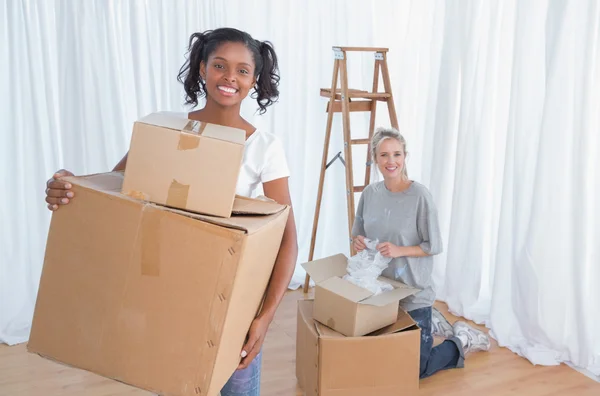 Young friends unpacking in their new home and smiling at camera — Stock Photo, Image