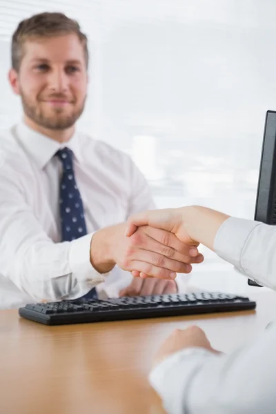 Smiling businessman shaking hands with a co worker — Stock Photo, Image