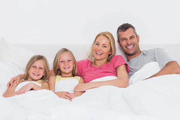 Retrato de uma família deitada na cama — Fotografia de Stock