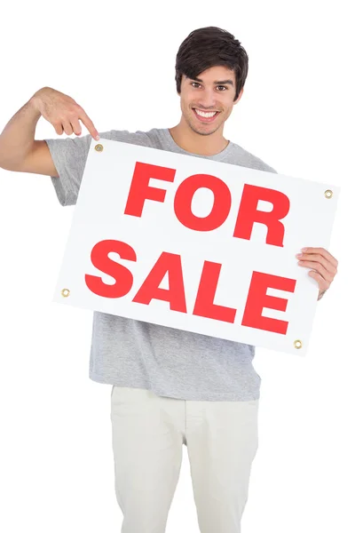 Улыбающийся мужчина указывает на знак продажи — стоковое фото