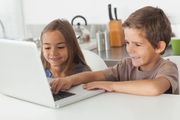 Geschwister nutzen gemeinsam einen Laptop — Stockfoto