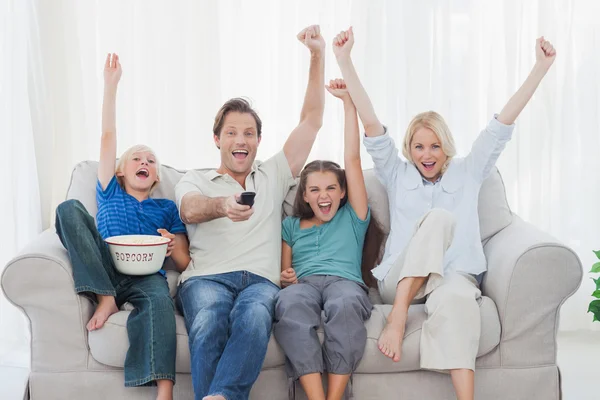 Family watching television and raising arms — Stock Photo, Image