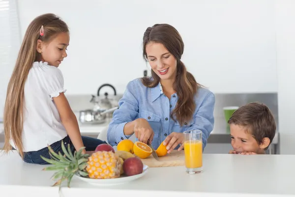 Mulher cortando uma laranja para seus filhos — Fotografia de Stock