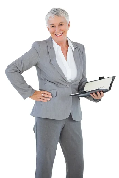 Mujer de negocios sonriente sosteniendo diario con su mano en la cadera — Foto de Stock