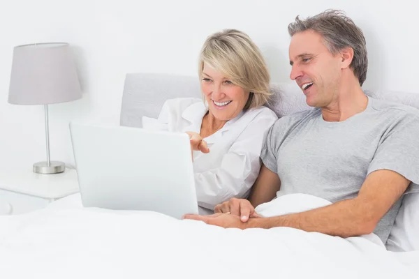 Gelukkige paar met laptop in bed — Stockfoto