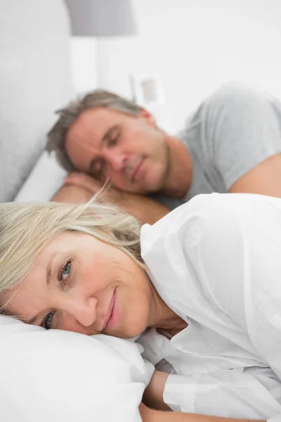 Femme éveillée alors que son partenaire dort au lit — Photo