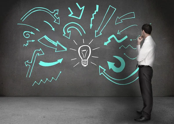 Empresario mirando una pared con dibujos de flechas — Foto de Stock