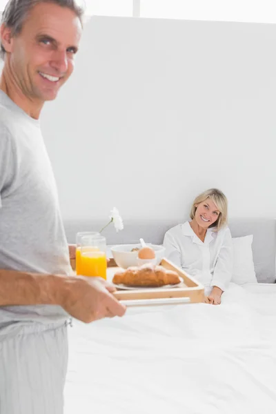 微笑男子躺在床上使早餐，他的搭档 — 图库照片