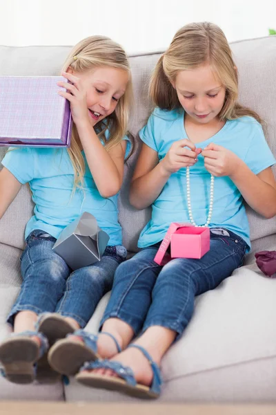 Twins unwrapping birthday gift sitting on a couch — Stock Photo, Image