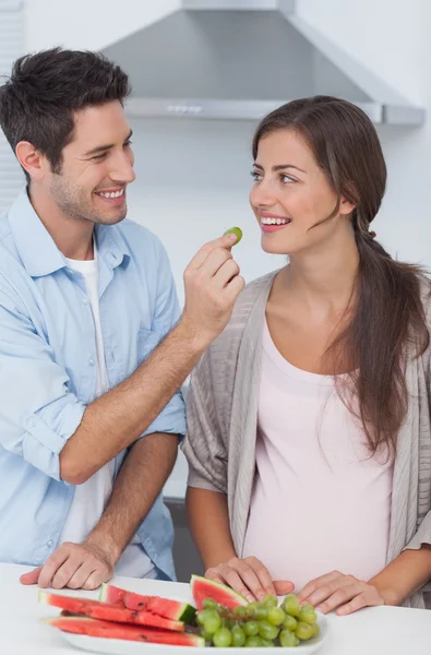 Homme donnant un raisin à sa partenaire enceinte — Photo