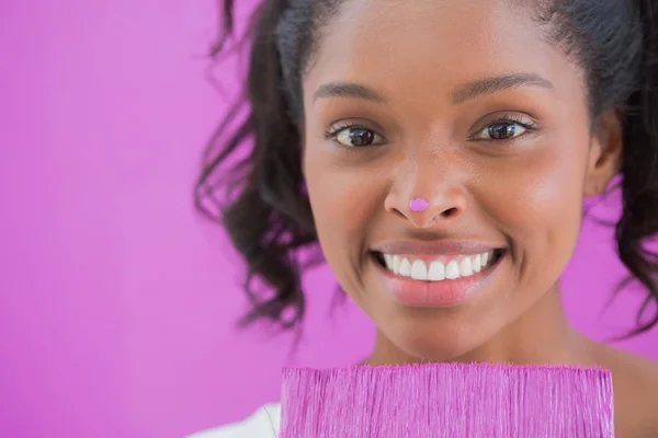 Happy woman holding paintbrush with paint on her nose — Stock Photo, Image