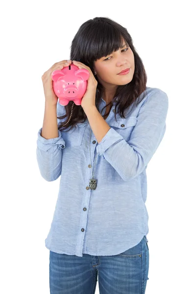 Jonge vrouw schudden haar piggy bank — Stockfoto