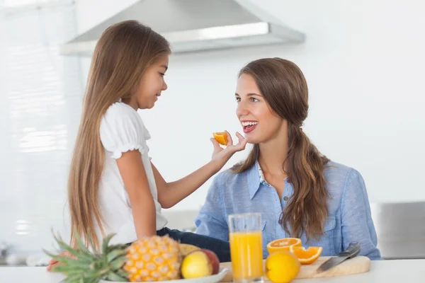 Liten flicka ger ett orange segment till hennes mor — Stockfoto