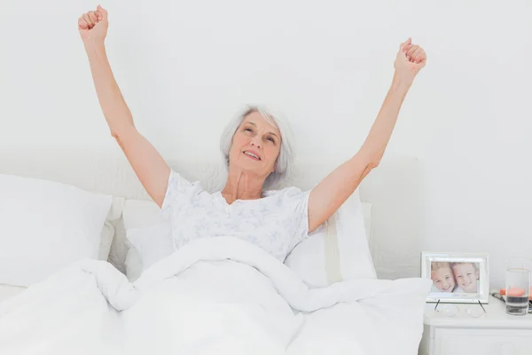 Frau wacht auf und hebt die Arme im Bett — Stockfoto