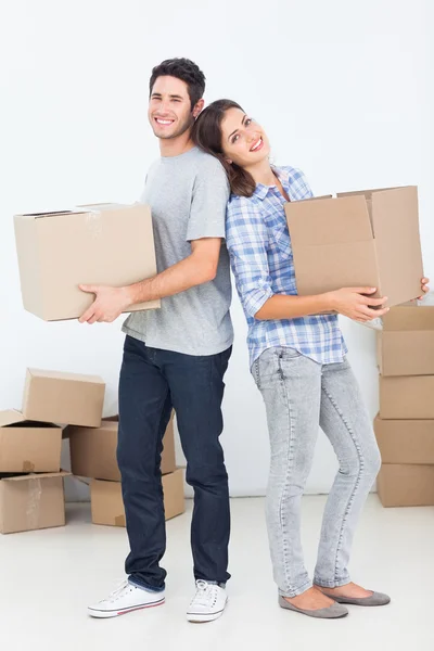 Husband and wife carrying boxes in their new house — Stock Photo, Image