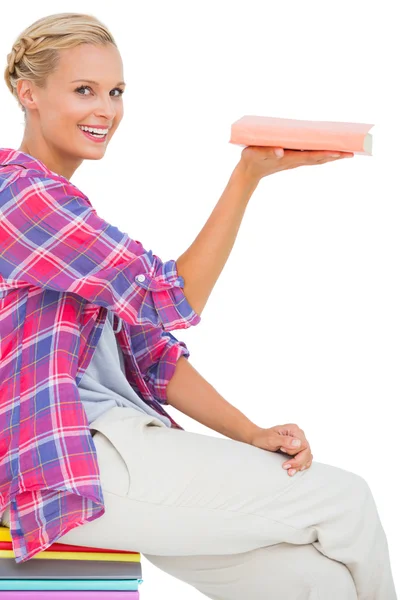 Beautiful woman showing a book and smiling at camera — Stock Photo, Image