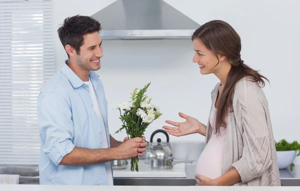 男は彼の妊娠中のパートナーに花を与える — ストック写真