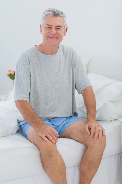 Homem alegre sentado na cama — Fotografia de Stock