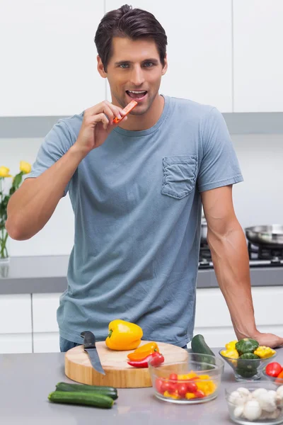 Homem atraente comendo uma fatia de pimentão — Fotografia de Stock