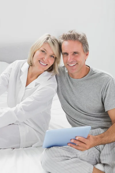 Couple using their tablet pc smiling at camera — Stock Photo, Image