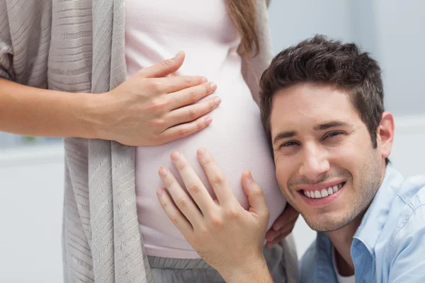 Uomo ascoltando la pancia della moglie incinta — Foto Stock