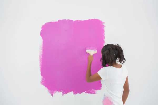 Jonge vrouw haar muur in roze schilderij — Stockfoto