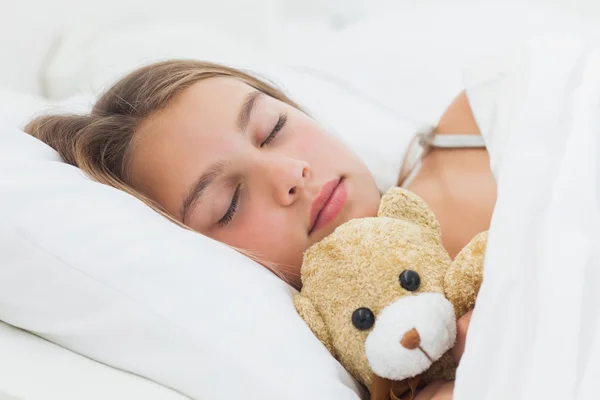 Chica alegre durmiendo con su osito de peluche — Foto de Stock