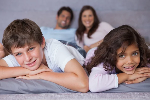 Sorridente fratello e sorella sdraiati sul letto — Foto Stock