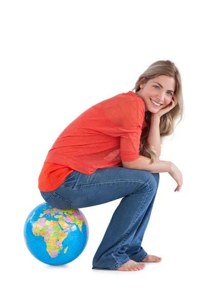 Smiling woman sitting on a globe — Stock Photo, Image