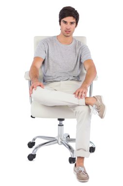 Serious man sitting on a swivel chair clipart