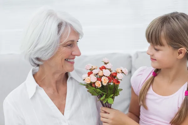 Милая девушка дарит кучу цветов своей бабушке — стоковое фото