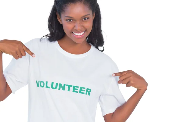 Uśmiechnięta młoda kobieta sobie wolontariuszy tshirt i wskazując na to — Zdjęcie stockowe