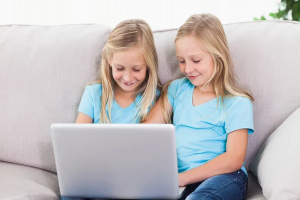 Gêmeos jovens usando um laptop juntos — Fotografia de Stock